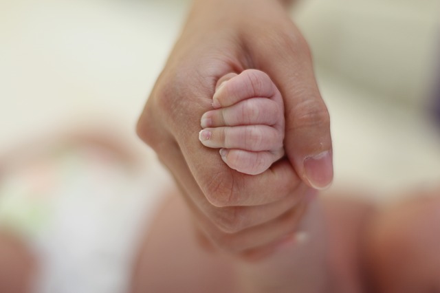 ruka novorozeněte v ruce matky
